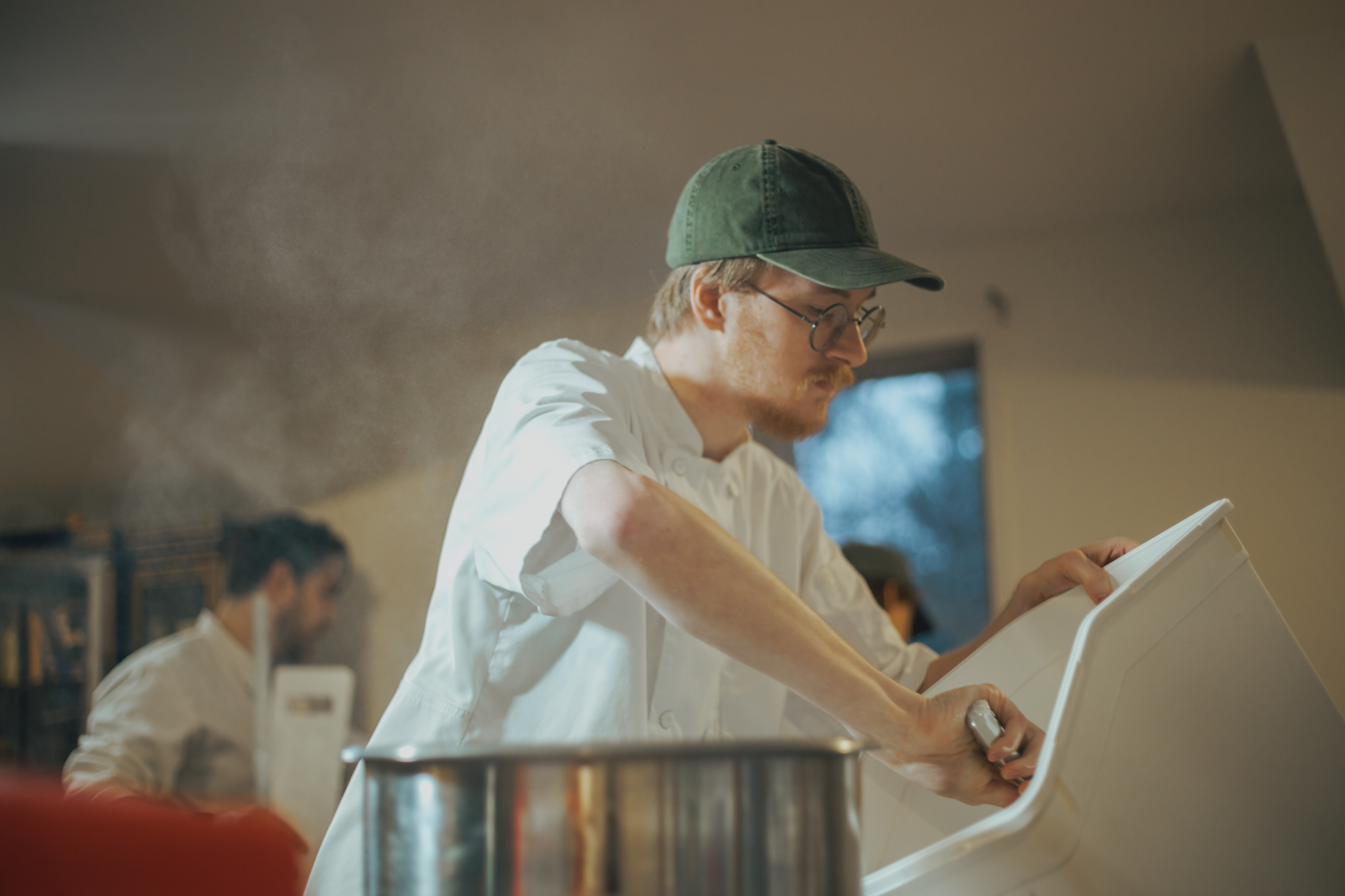 Baker working in kitchen with steam